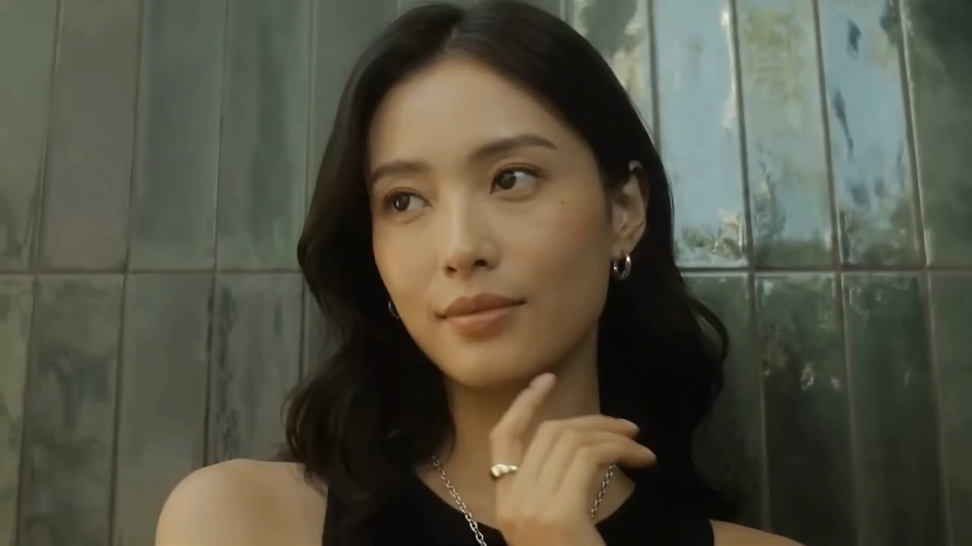 Model wearing a silver chain necklace, hoop earrings and a gold ring